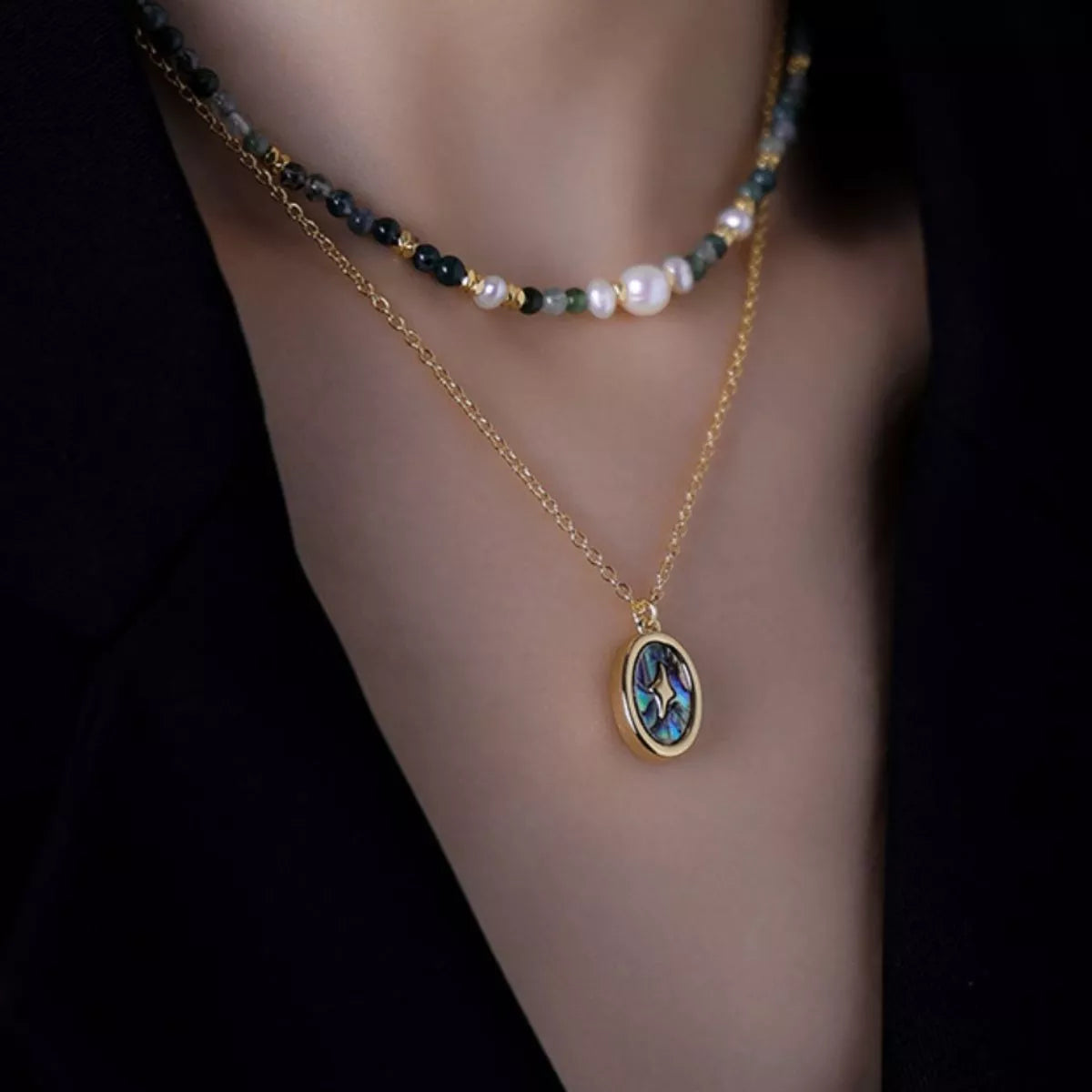 Gold-plated pendant necklace set with oval blue charm on beaded freshwater pearl strand