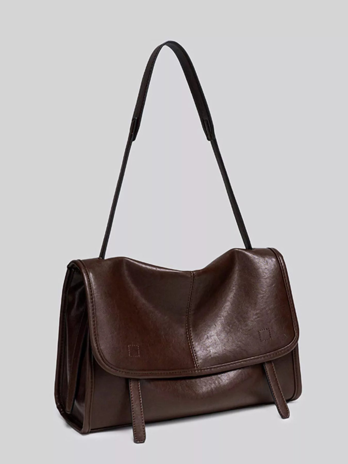 Brown vegan leather shoulder bag with front flap, side tassel straps, and top handles