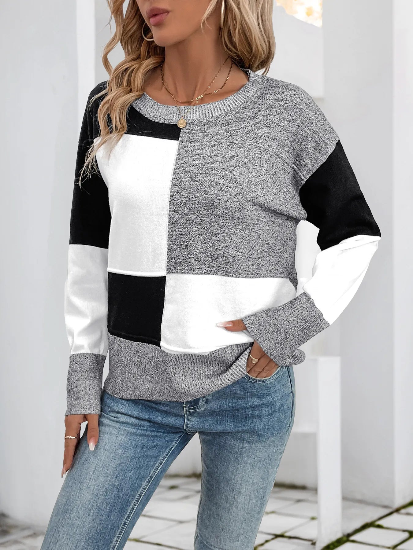 Grey and white color-block knit sweater with black panels, ribbed crew neck and cuffs