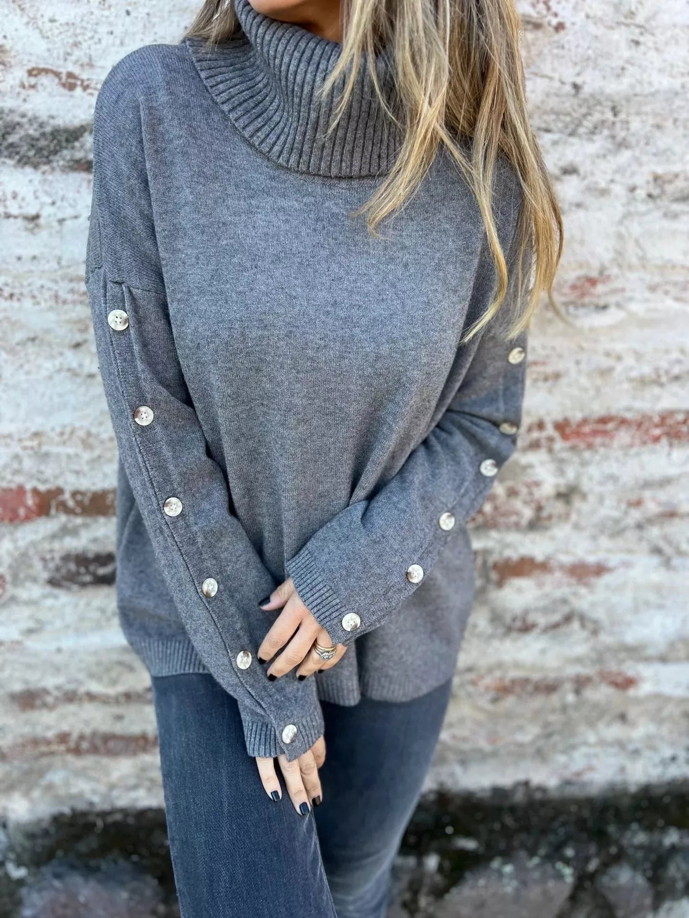 Gray turtleneck long sleeve sweater with button-detail cuffs and twisted rib collar