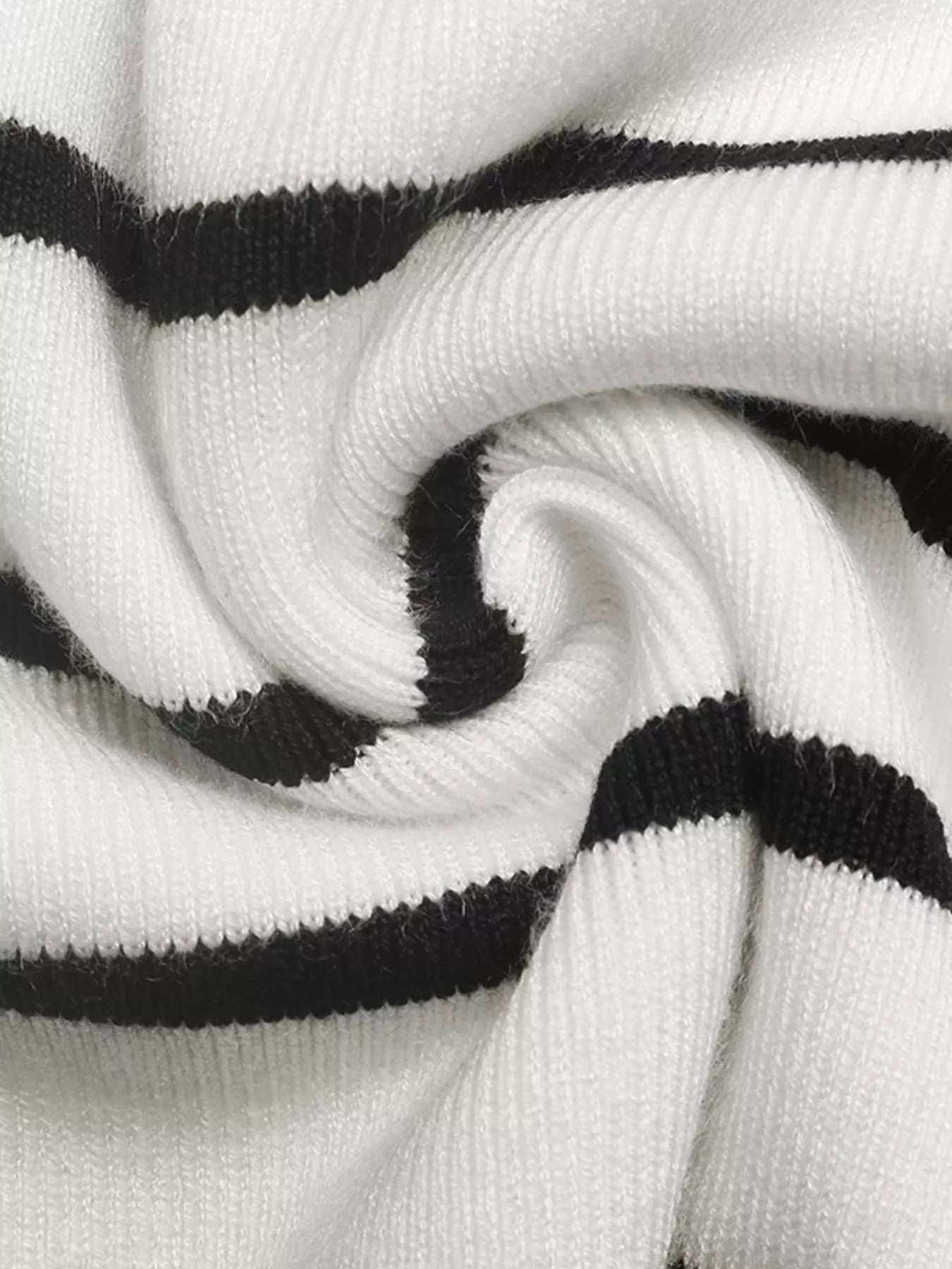 White knit fabric with black horizontal stripes, folded for close-up texture