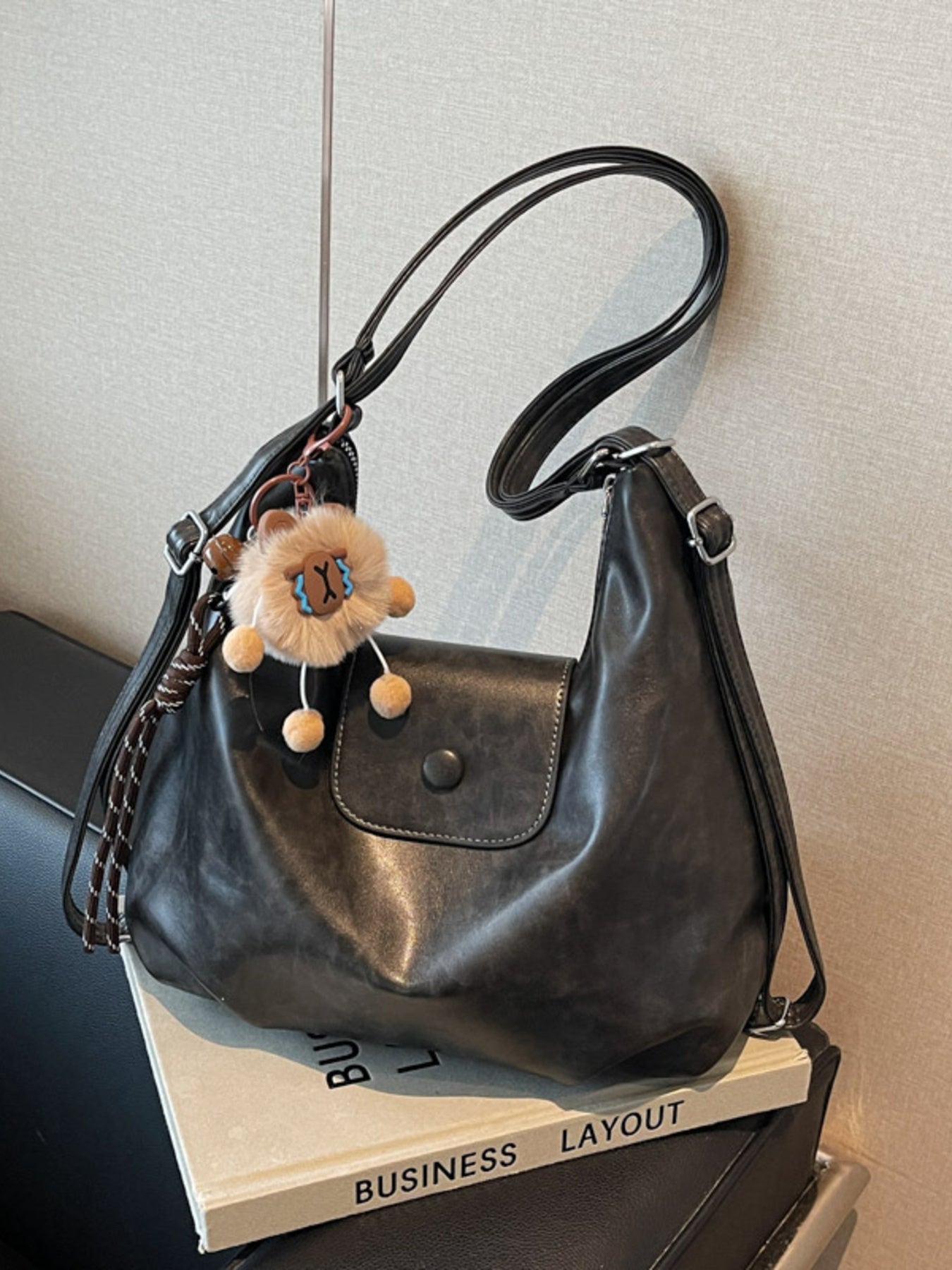 Adjustable Strap Shoulder Bag in black PU leather, medium size, with pom-pom keychain