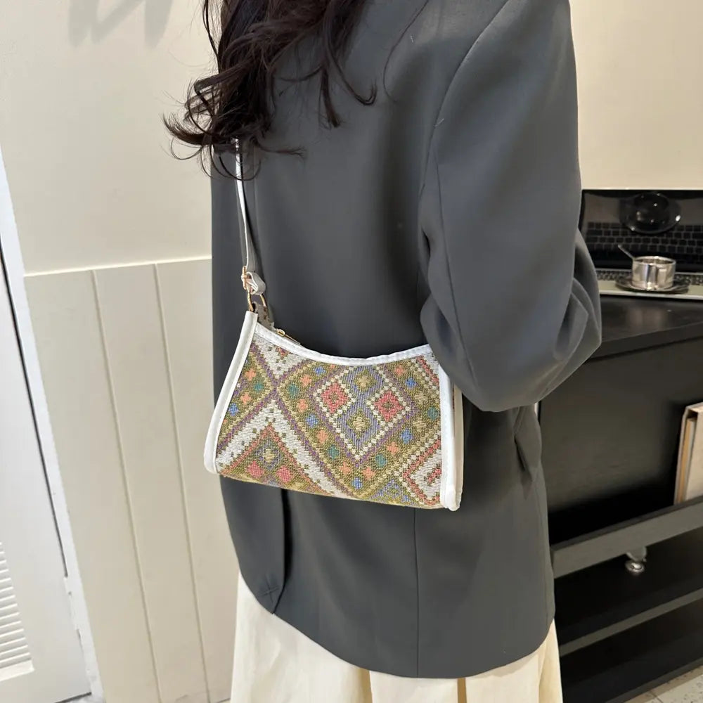 Light-colored crossbody bag with multicolor diamond print, worn at hip on a model