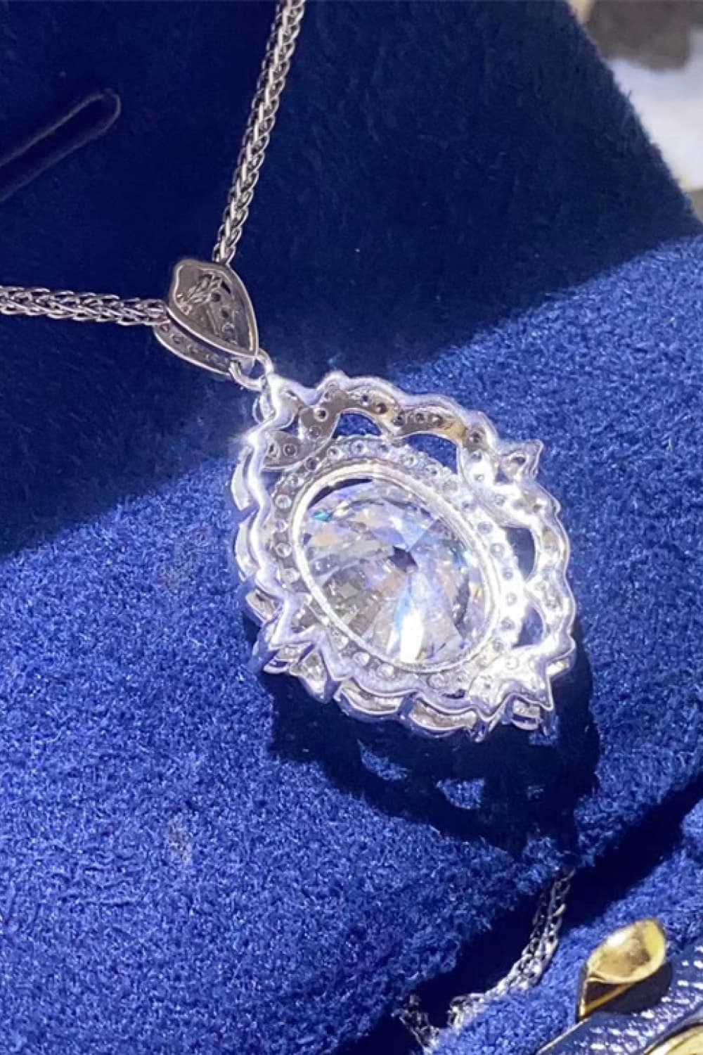 Sterling silver moissanite pendant necklace shown at angle with round center and halo