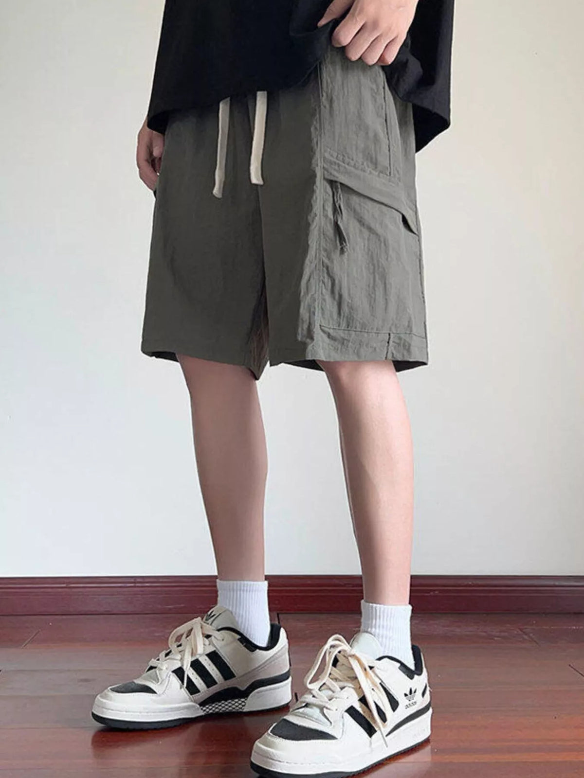 Gray-green cargo shorts with drawstring waist and utility side pocket flaps