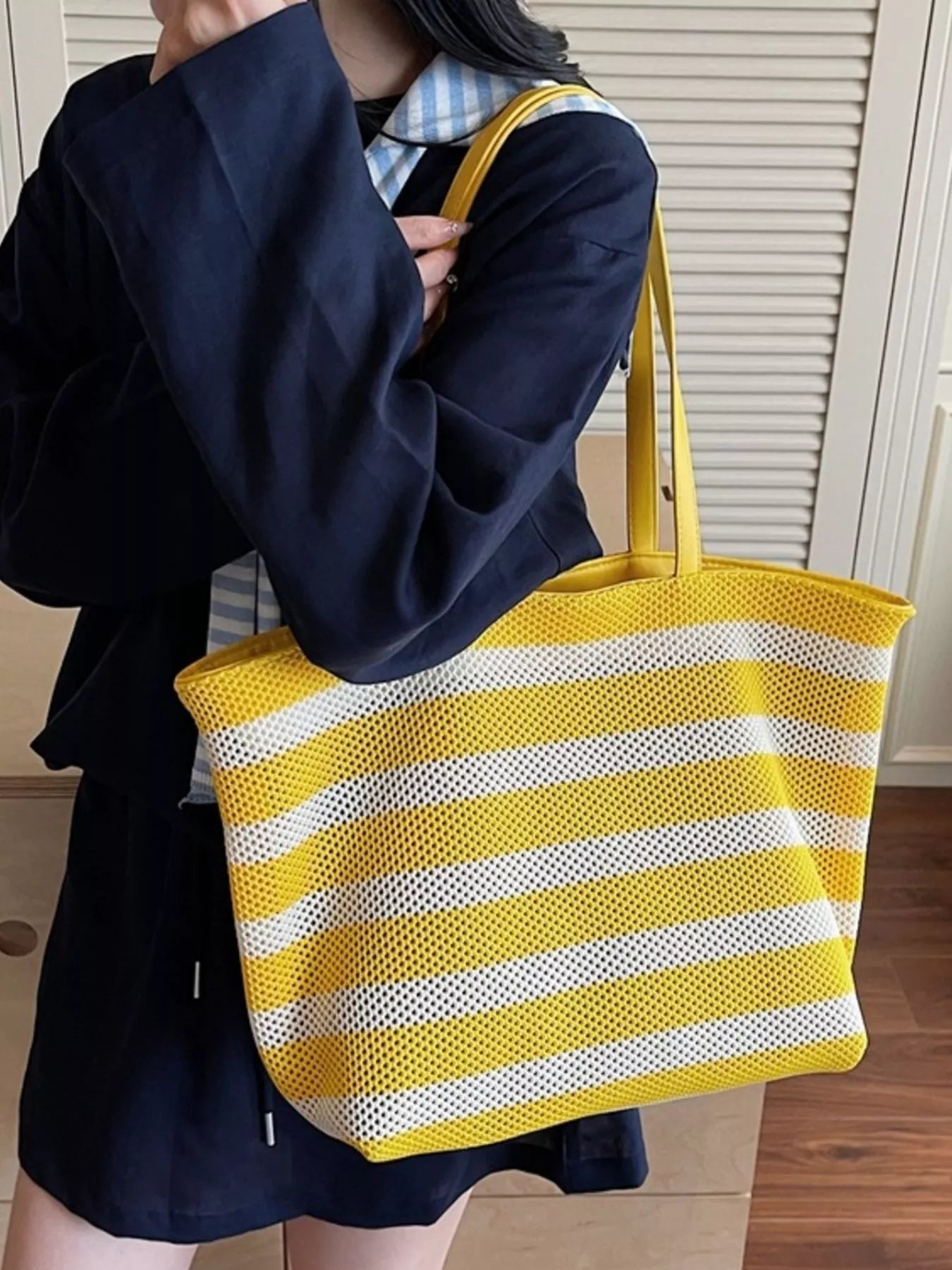 Yellow and white striped mesh tote shoulder bag held by person, long handles