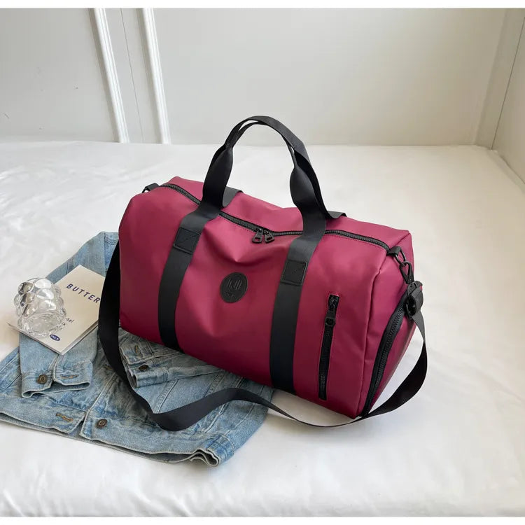Burgundy large waterproof duffel bag with black handles, shoulder strap, and front pocket