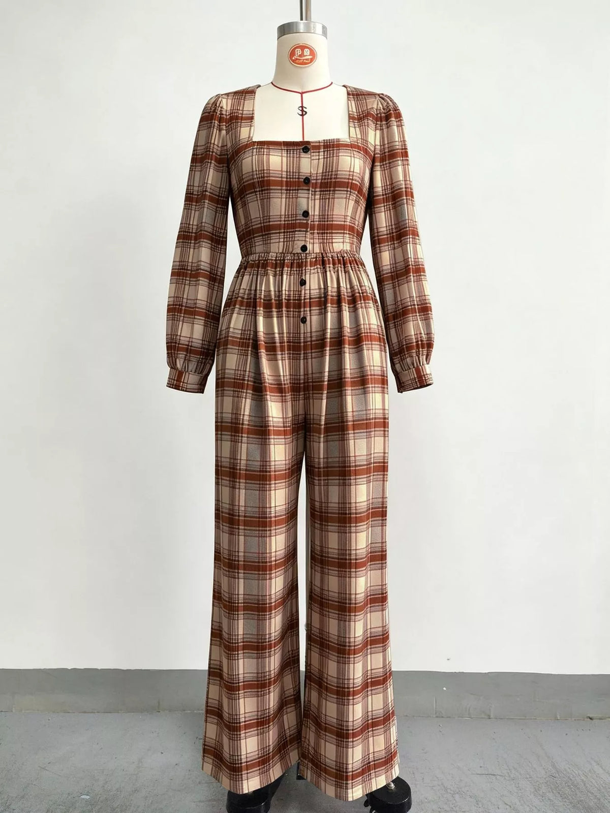 Plaid square-neck long-sleeve jumpsuit on mannequin with button bodice and wide legs