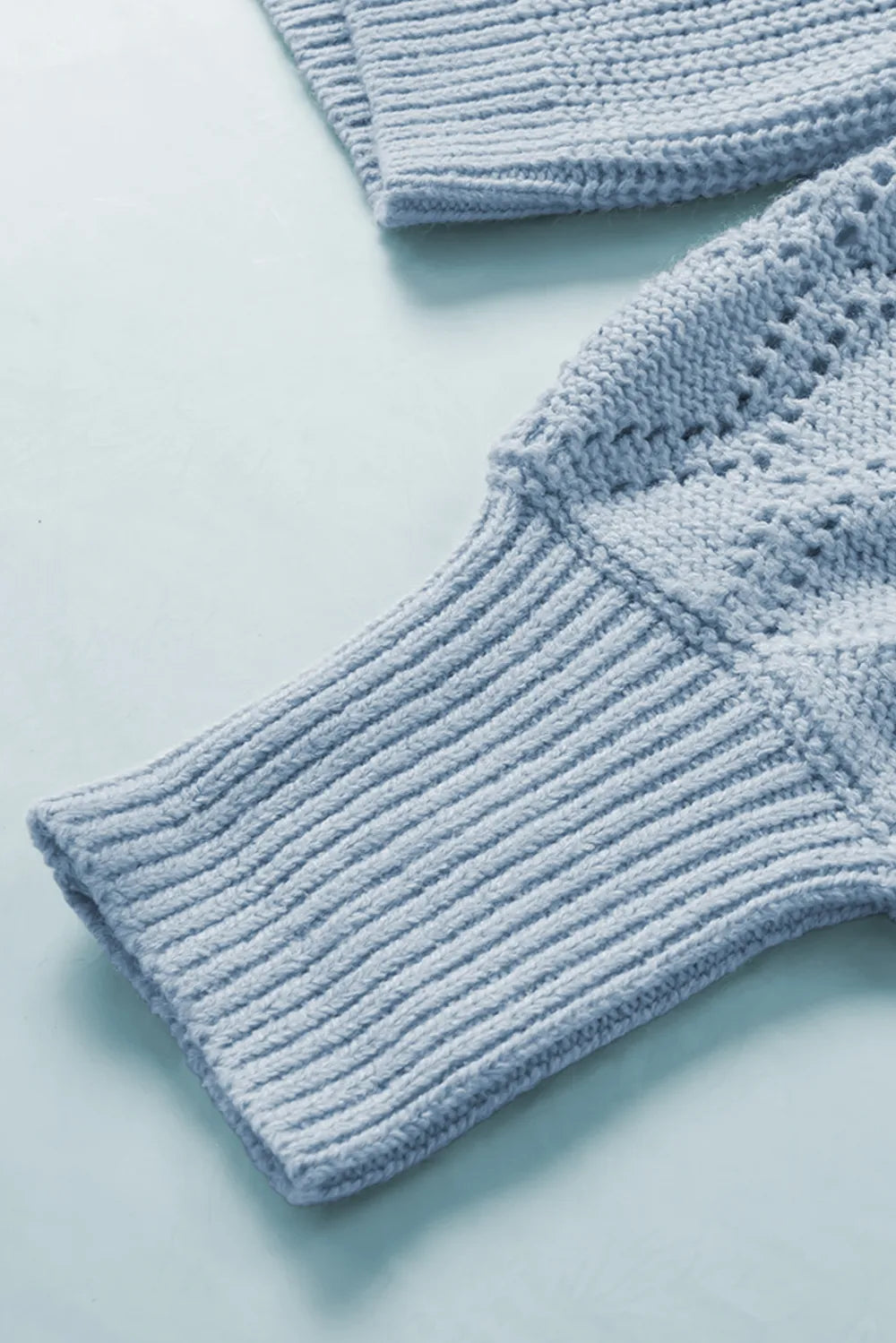 Light blue ribbed knit cuff and openwork pattern detail on cardigan sleeve