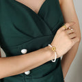 Freshwater pearl bracelet with gold flower charm, worn on wrist