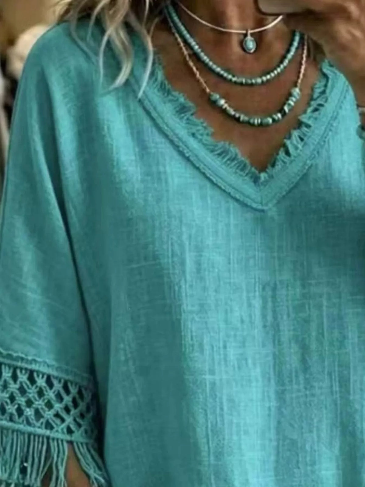 Turquoise V-neck blouse with textured fabric and crochet fringe sleeve detail