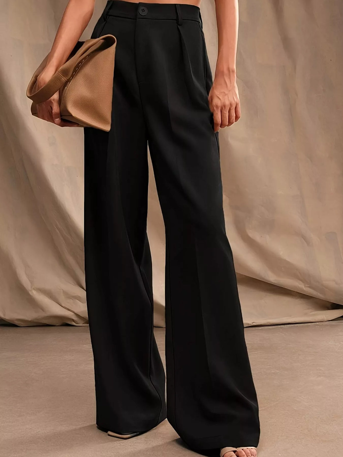 Black high-waisted pleated wide-leg pants, side view, belt loops and crease front