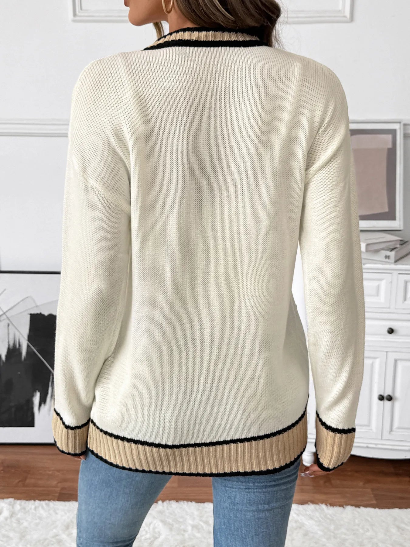 Cream knit cardigan back view with ribbed hem and black/tan contrast trim