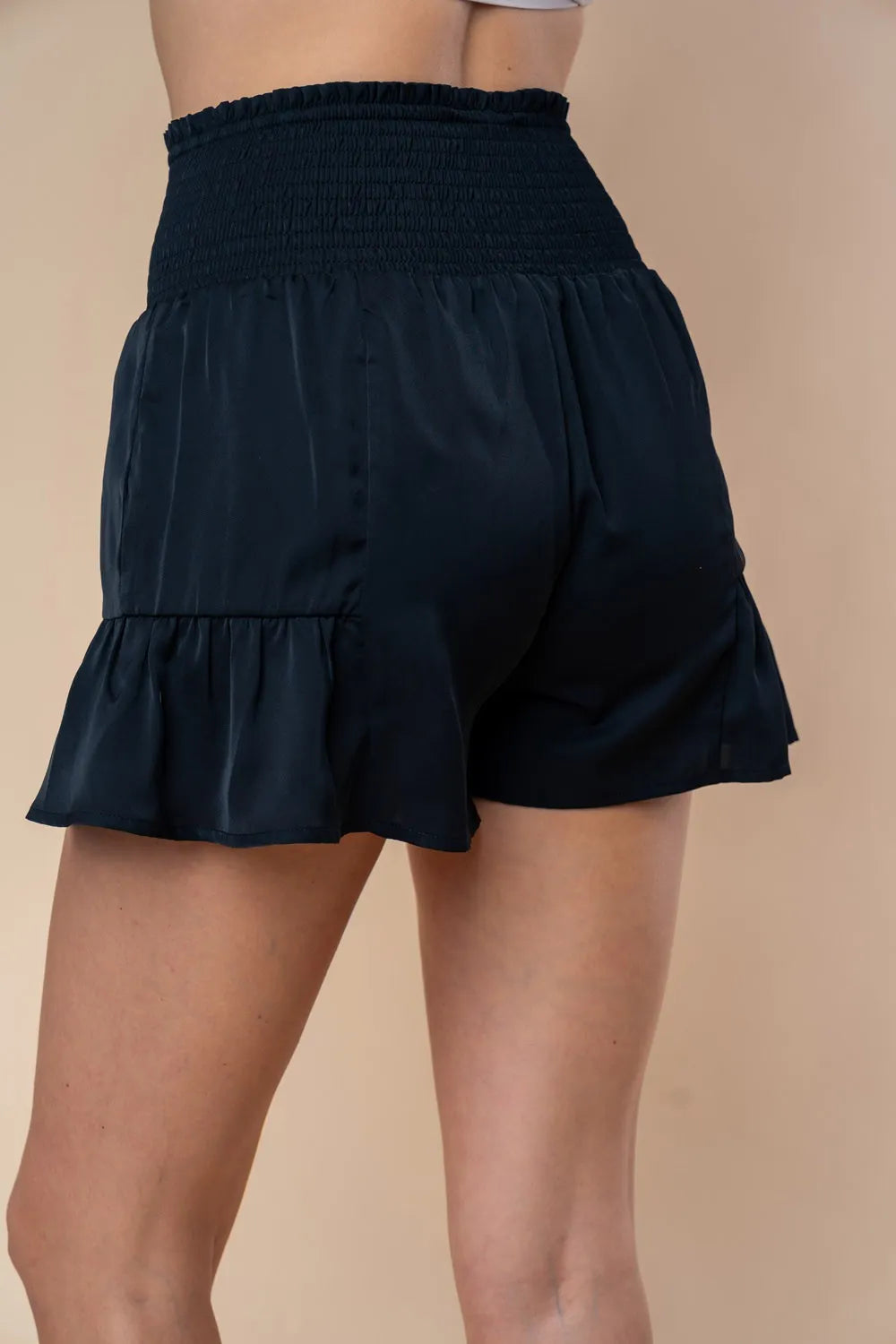 Smocked high-waisted shorts with layered tiers and bow detail, dark navy