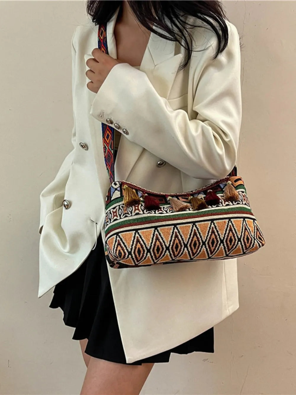 Tassel shoulder bag with adjustable strap, multicolor geometric print with tassel details.
