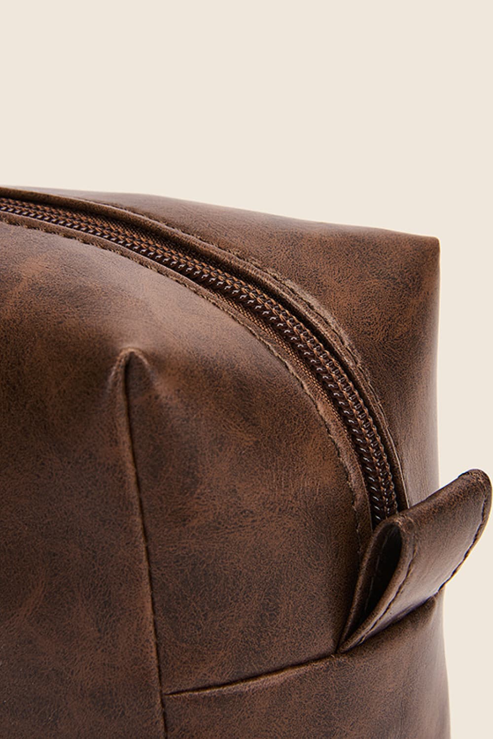 Close-up of brown vegan leather makeup bag zipper and corner handle loop