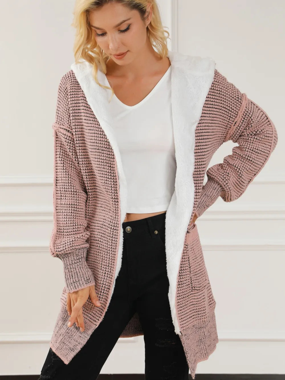 Open-front hooded winter coat with pockets, blush pink textured knit with white hood lining.