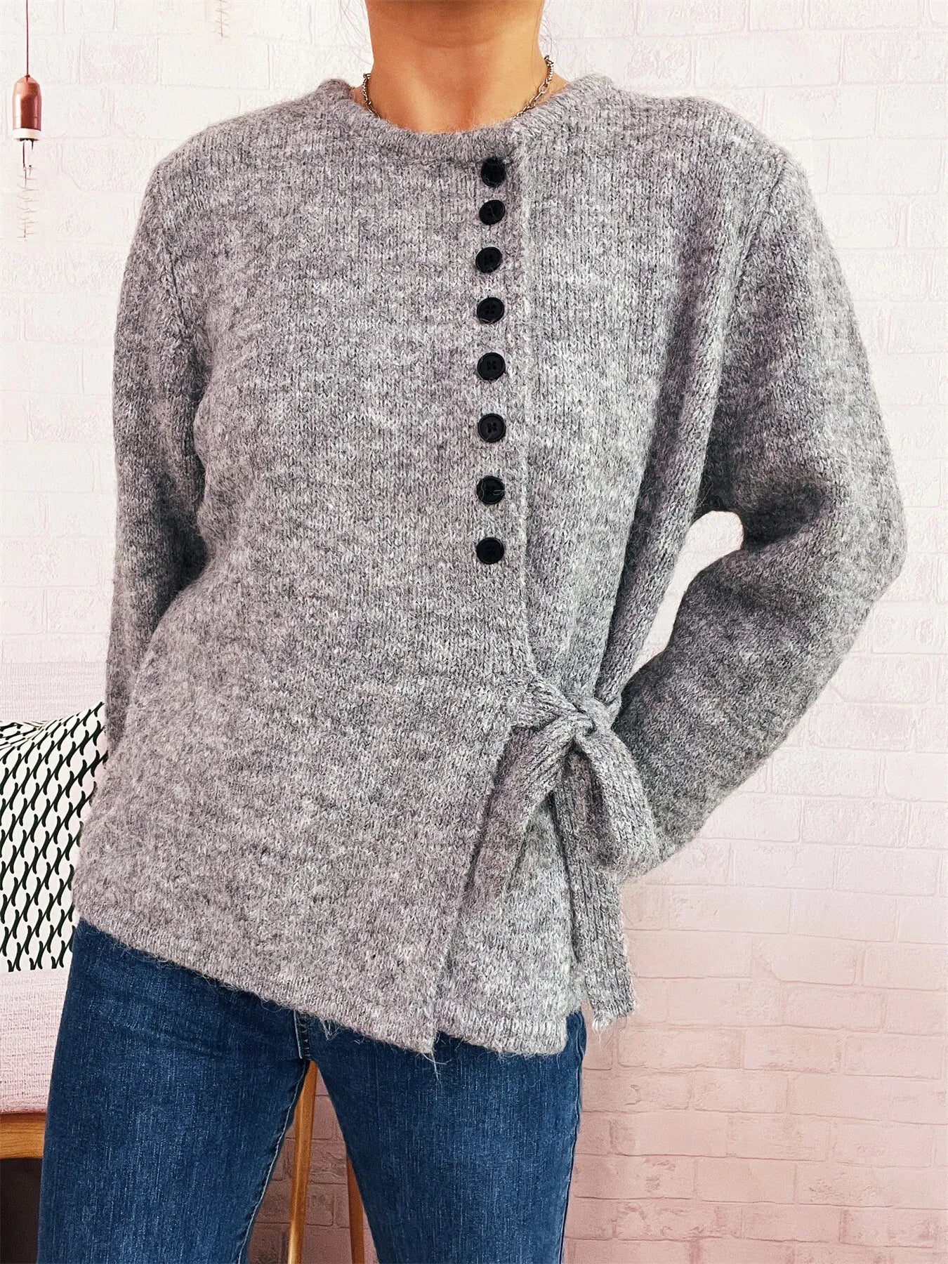 Gray button-front side-tie sweater with long sleeves and black buttons down center