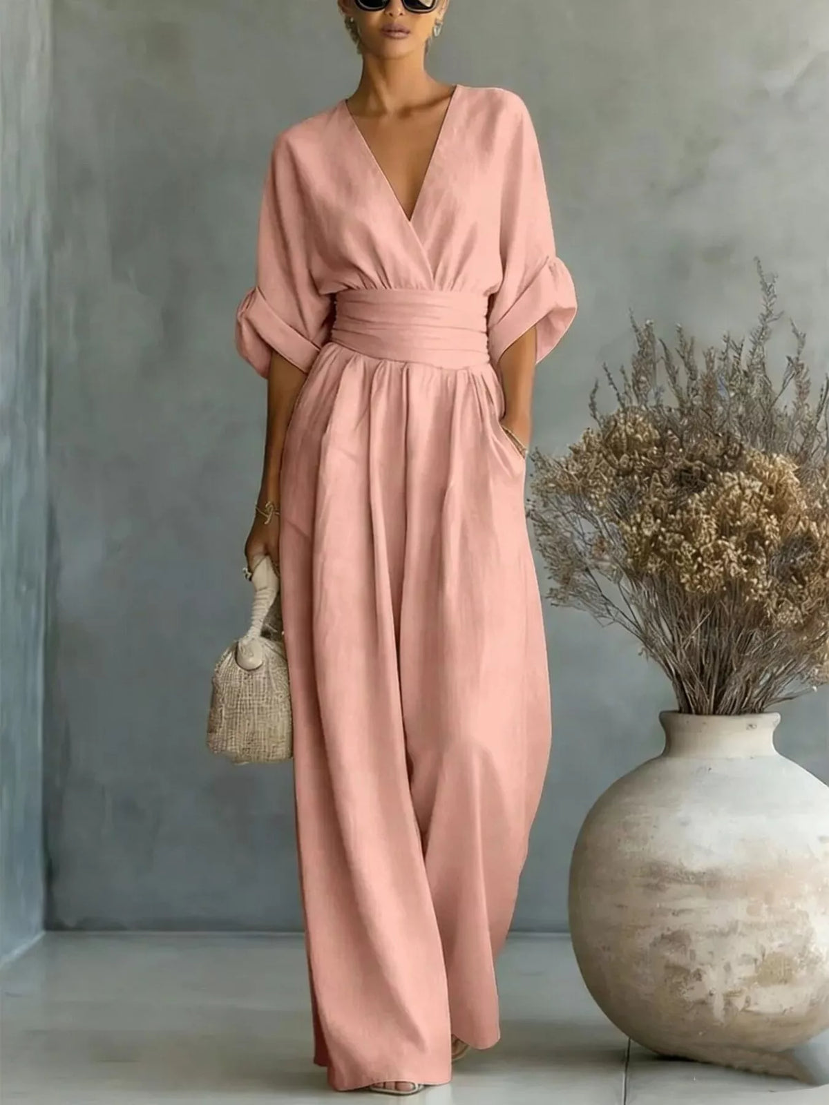 Dusty pink wide-leg jumpsuit with V-neck, draped half sleeves, and cinched waist