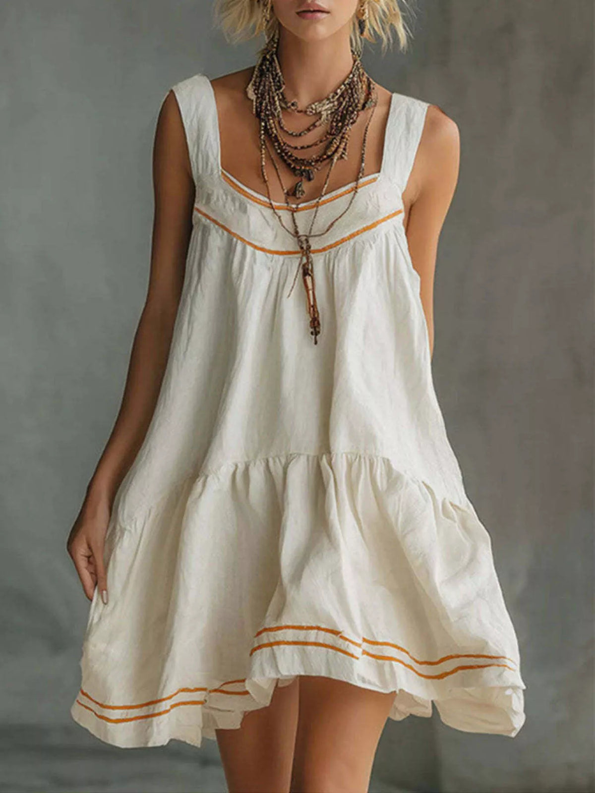 White sleeveless tiered ruffle mini dress with orange trim and layered hem