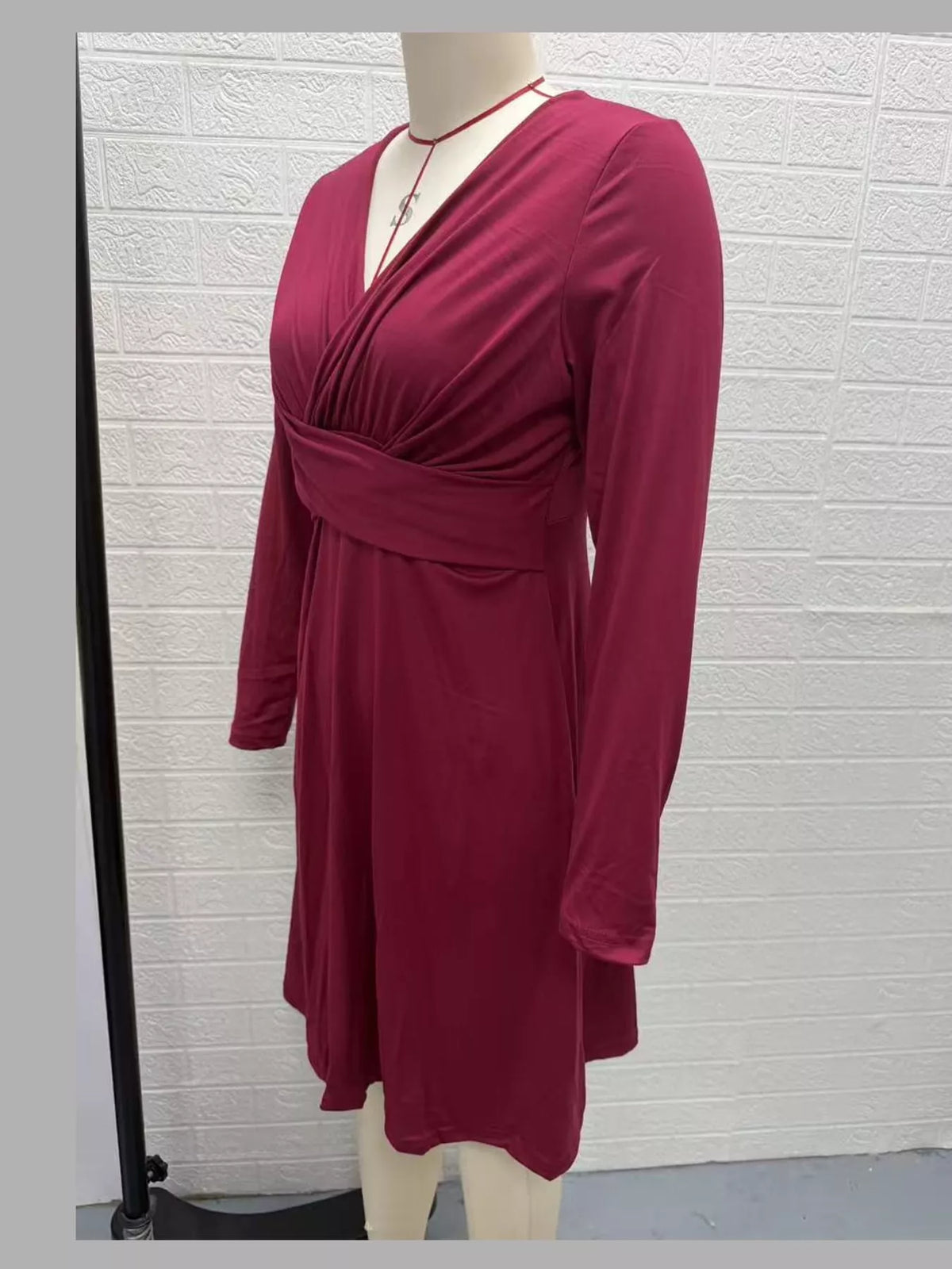Burgundy ruched midi dress with crisscross front and long sleeves, side view