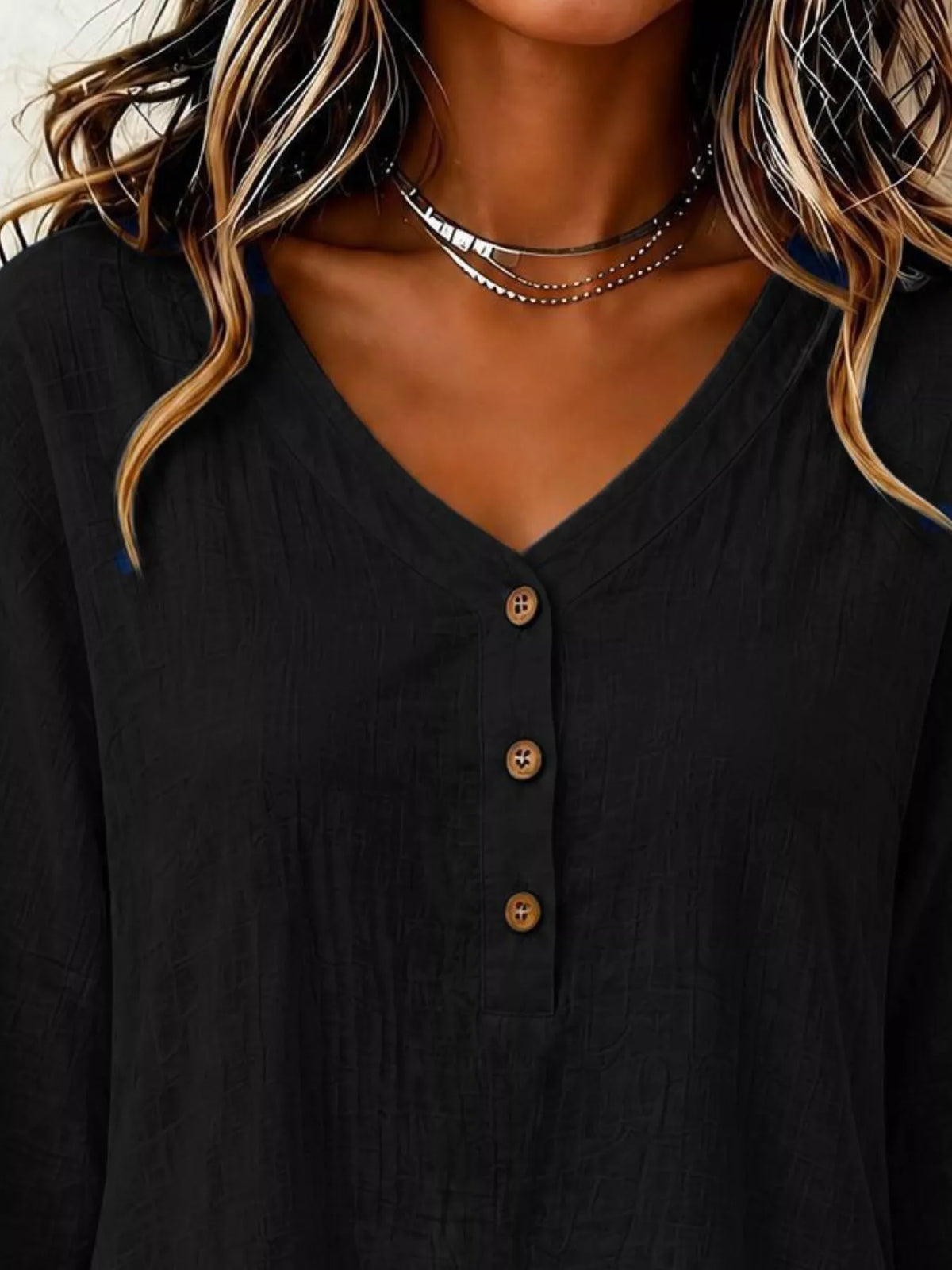 Black v-neck blouse close-up with 3-button placket and long sleeves
