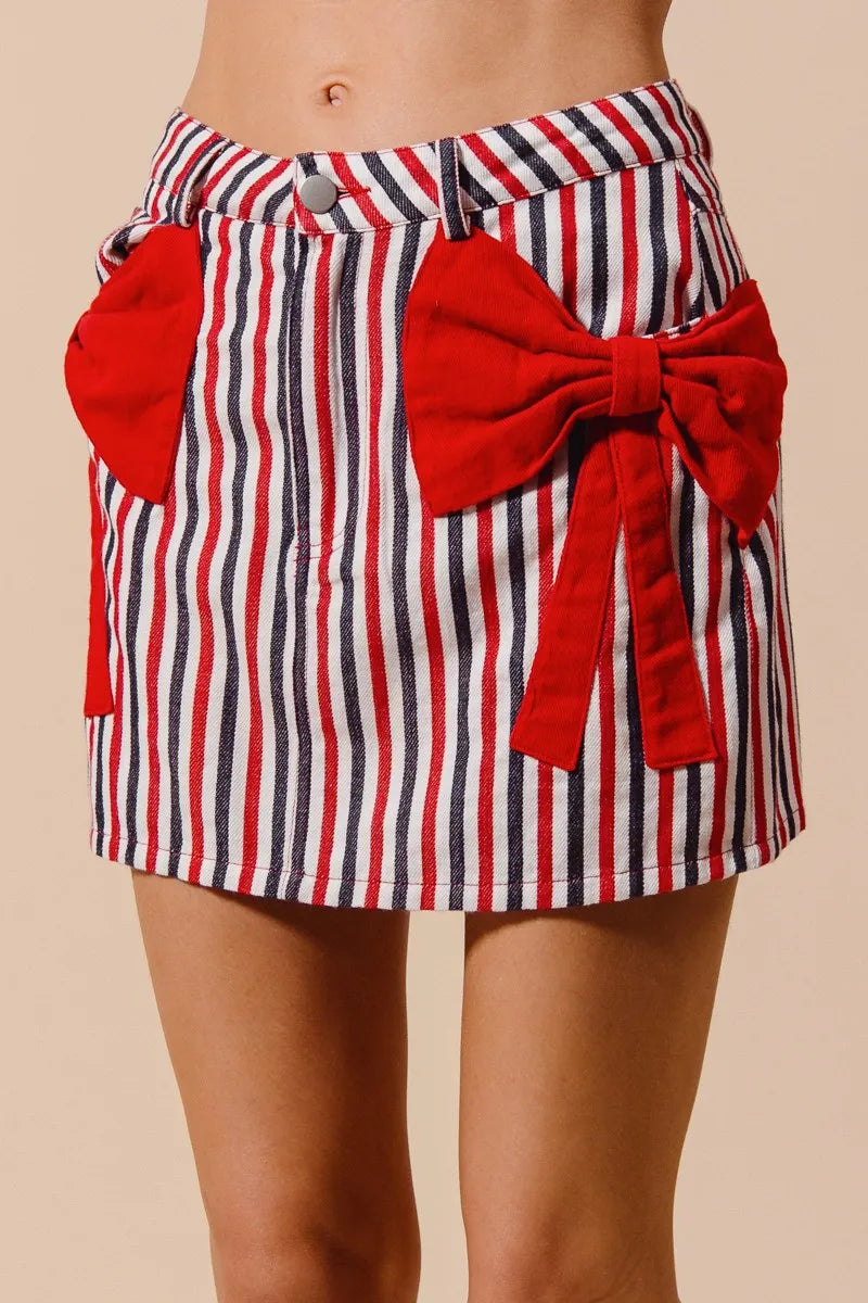 Striped denim mini skirt with large red bow tie and striped wrap pocket tabs