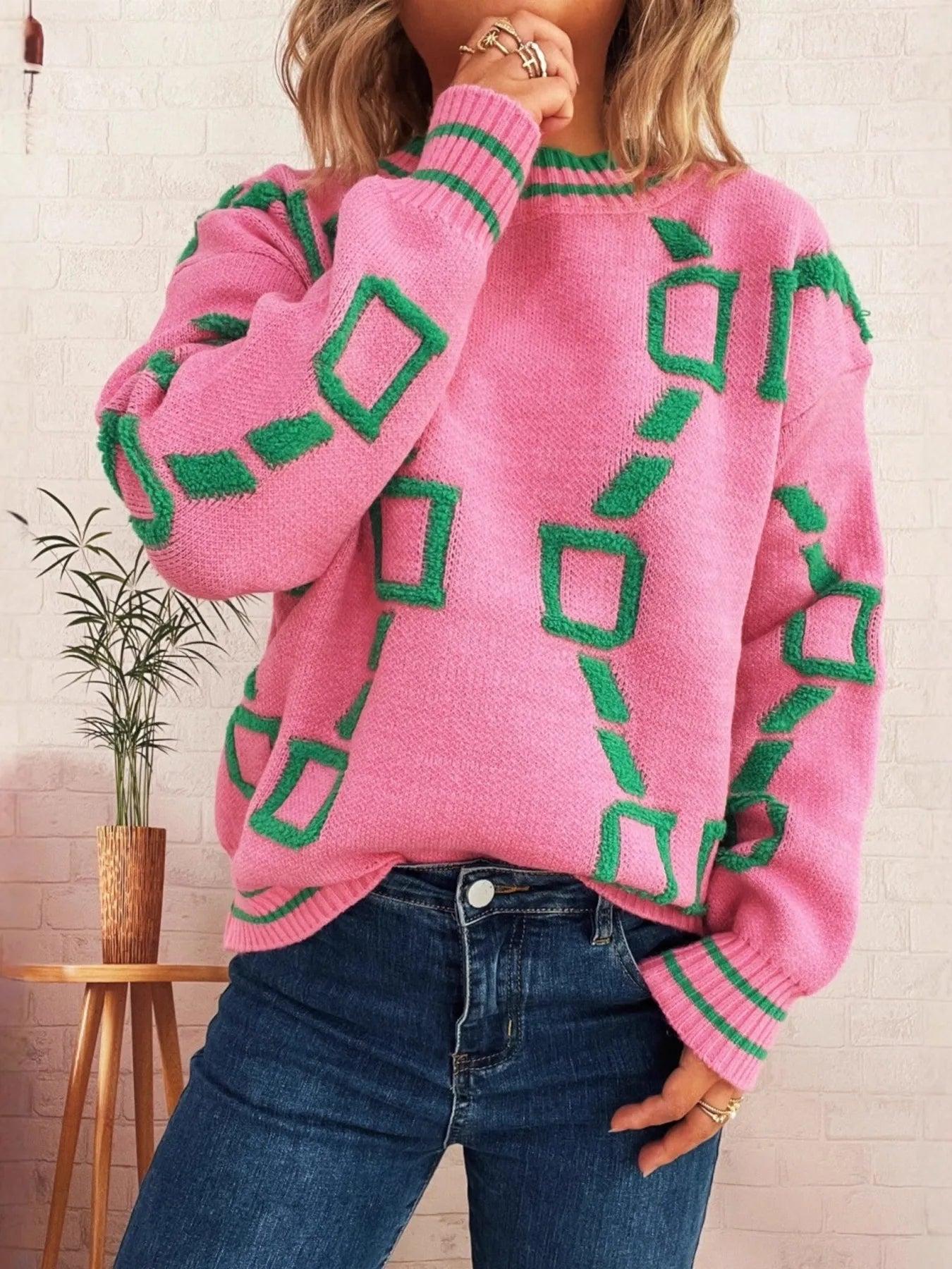 Pink long-sleeve sweater with green square motifs, ribbed round neck and striped cuffs
