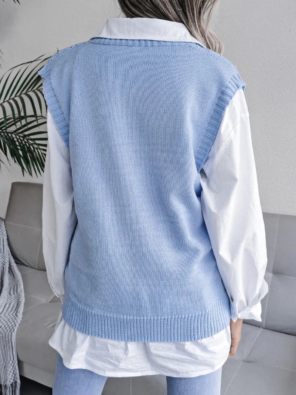 Light blue openwork V-neck sweater vest, sleeveless knit; back view with smooth hem.