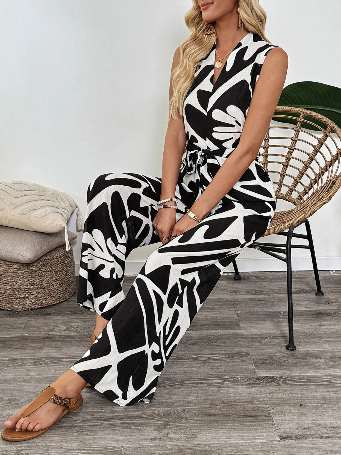 Printed wide-leg jumpsuit, sleeveless V-neck, black-and-white abstract print with tie waist.