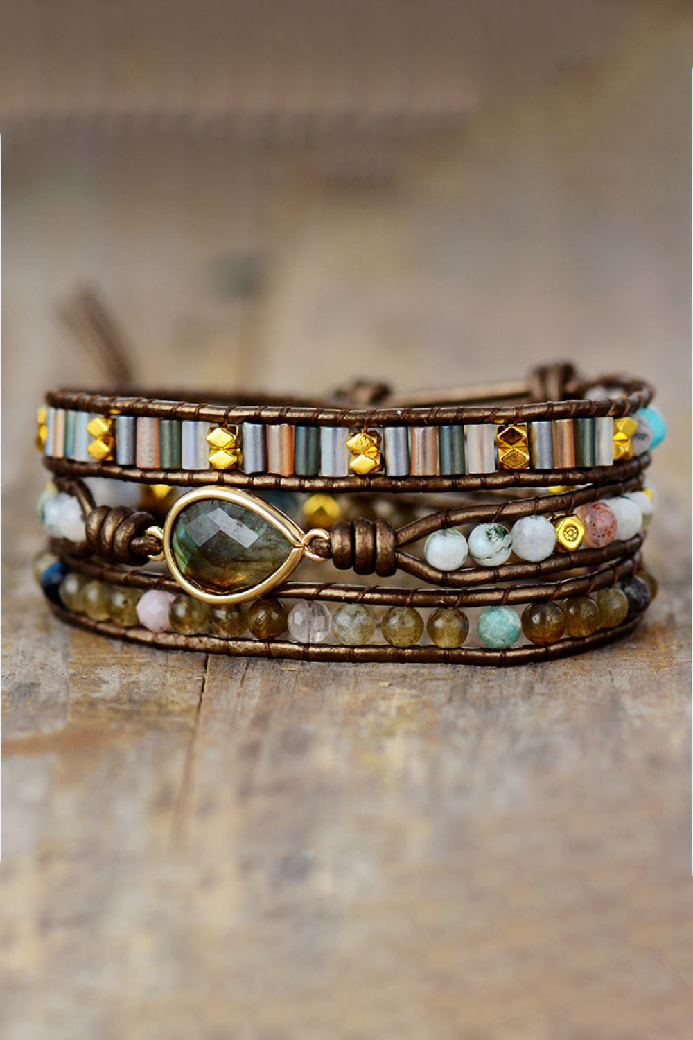 Triple-layer beaded bracelet with brown wrap, green oval charm, white and gold beads