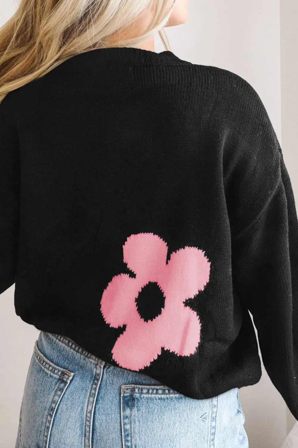 Black long-sleeve sweater with pink flower motif on the back