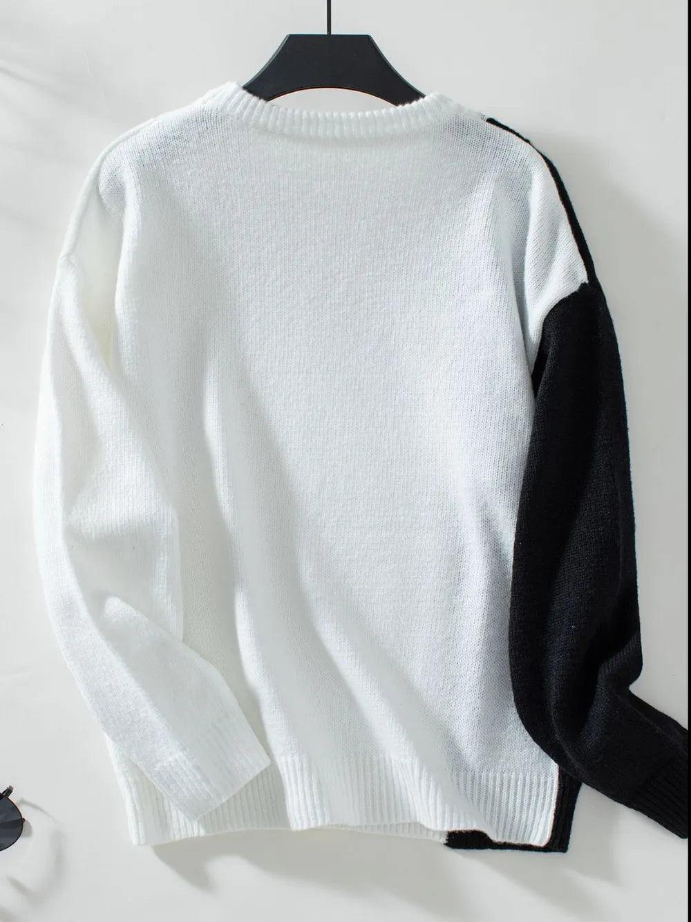 Two-tone cable knit sweater back with white knit and black sleeve accents on hanger