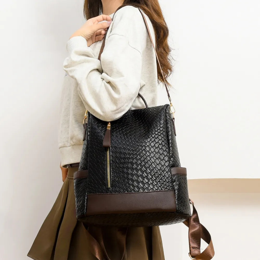 Vegan leather backpack bag on model in black with brown base panel and zip front