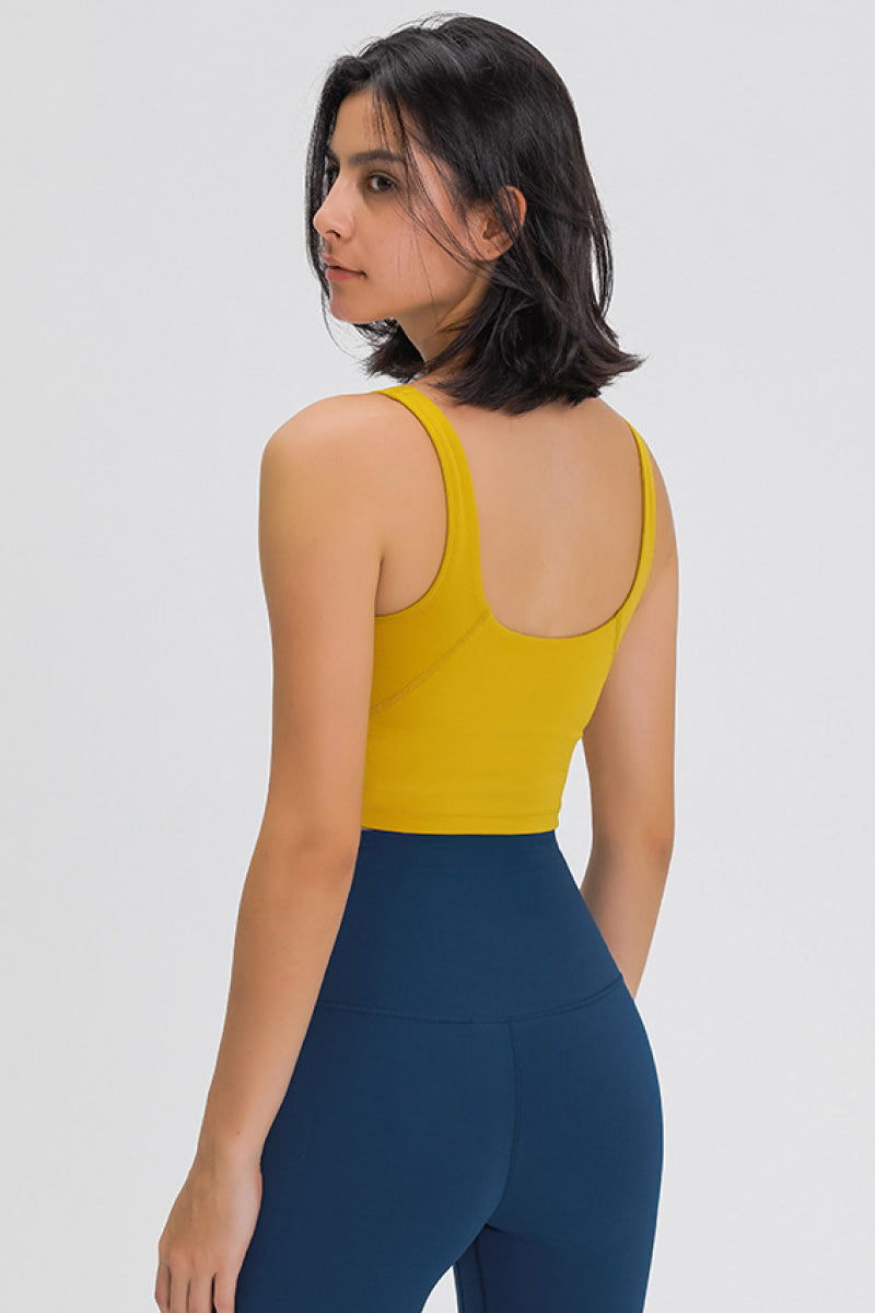 Mustard yellow scoop-back sports bra viewed from the back with wide straps