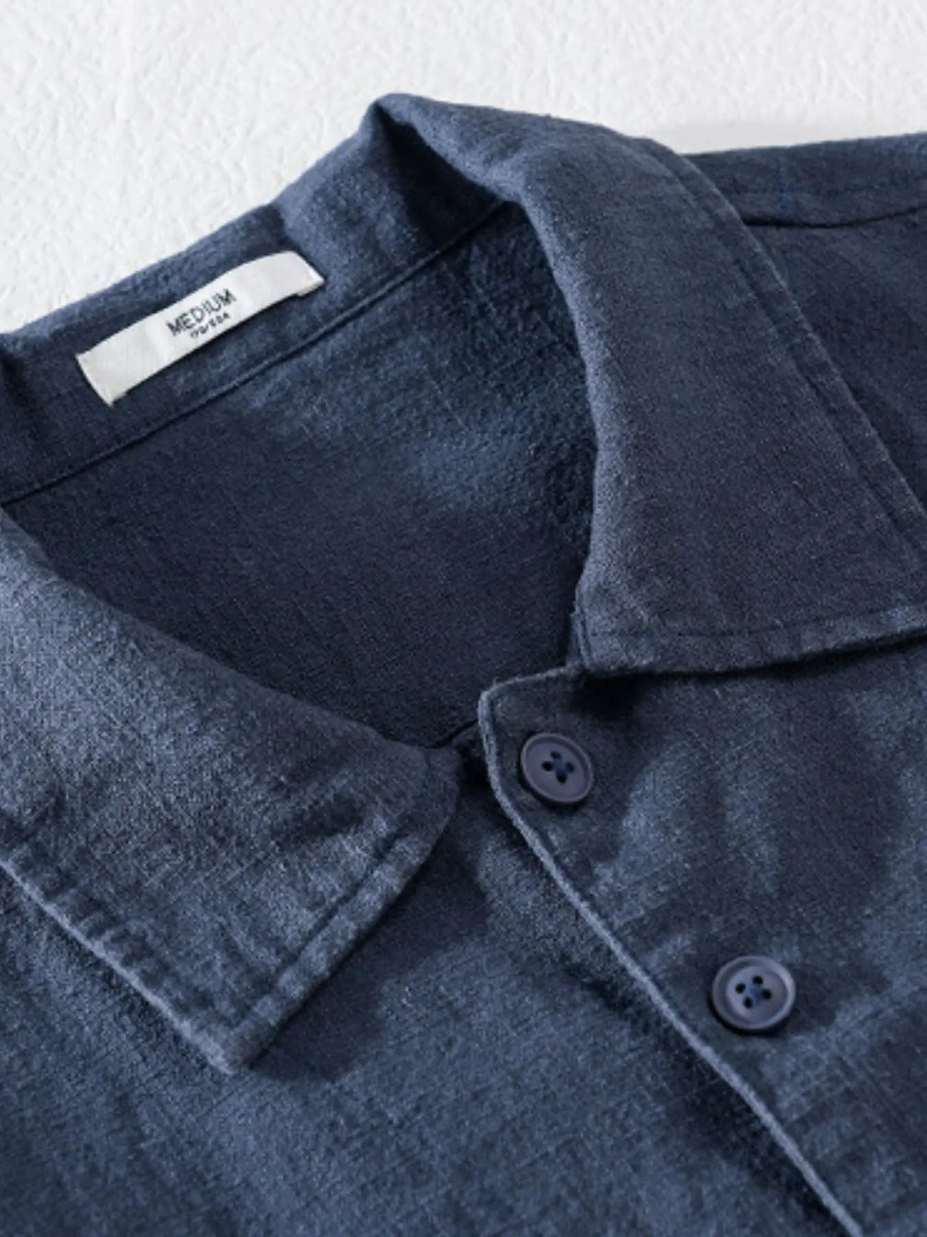 Dark blue button-up shirt collar with two button placket and chest pocket.