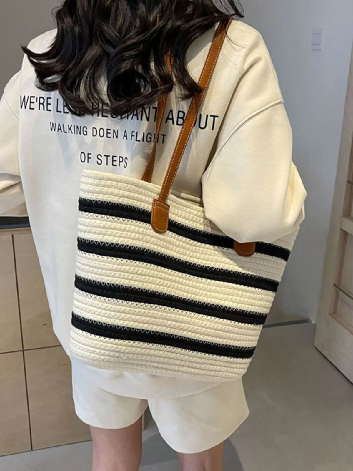 Striped straw tote bag with brown leather handles and white-and-navy horizontal stripe pattern