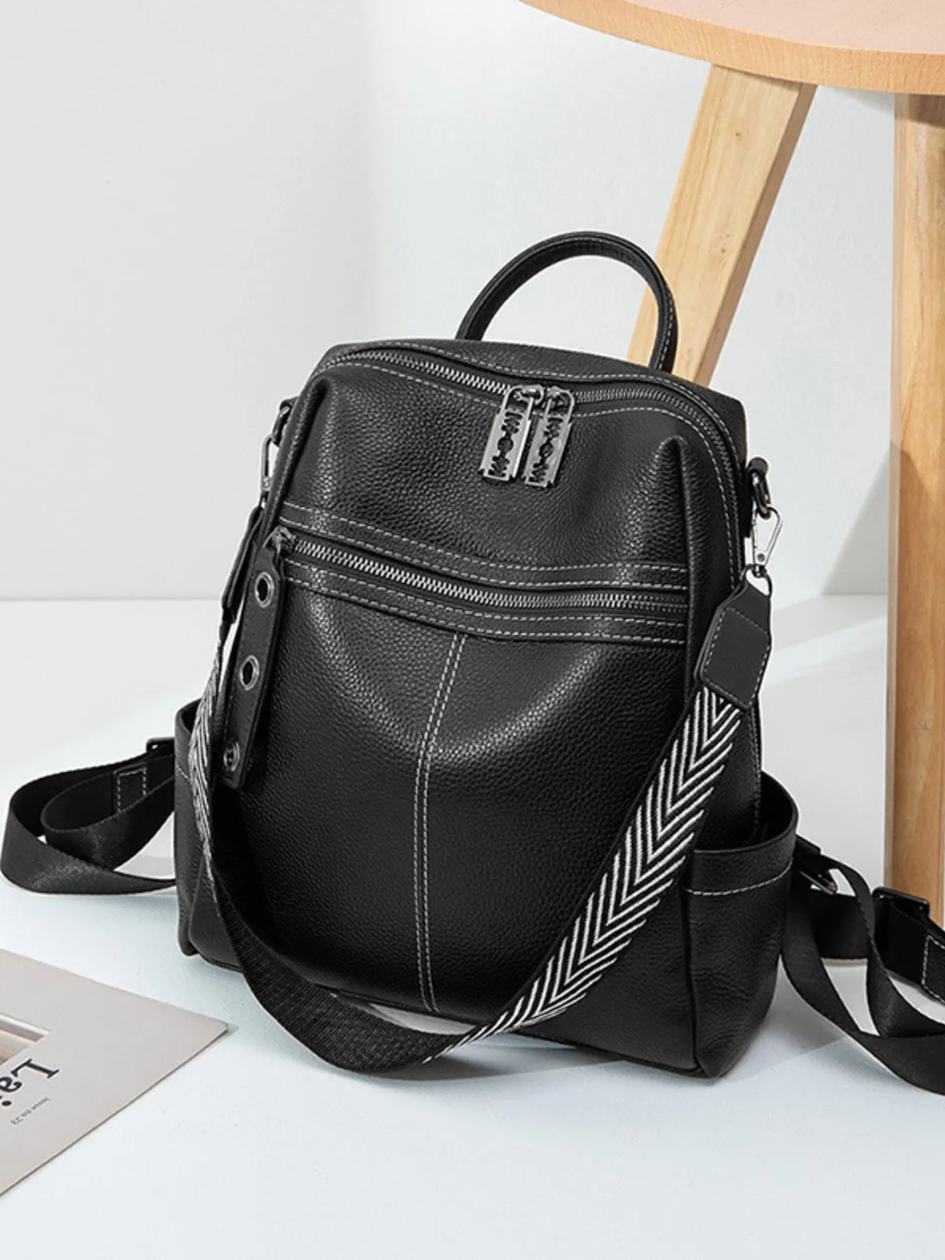 Black leather backpack bag with front zip pocket, top handle, adjustable strap