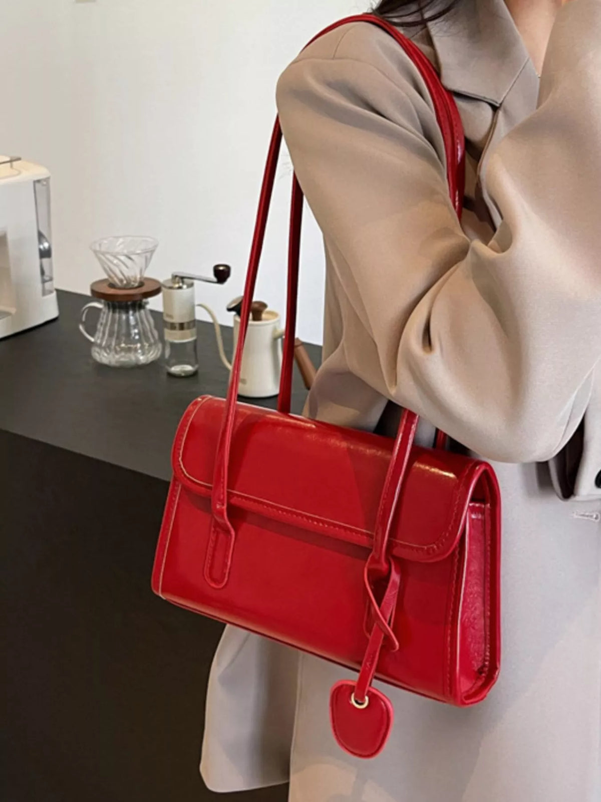 Small red shoulder bag on a model with long strap and flap front