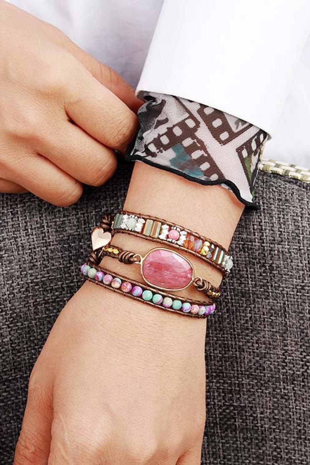 Beaded bracelet worn on wrist, oval pink stone, multicolor beads, and gold-tone settings