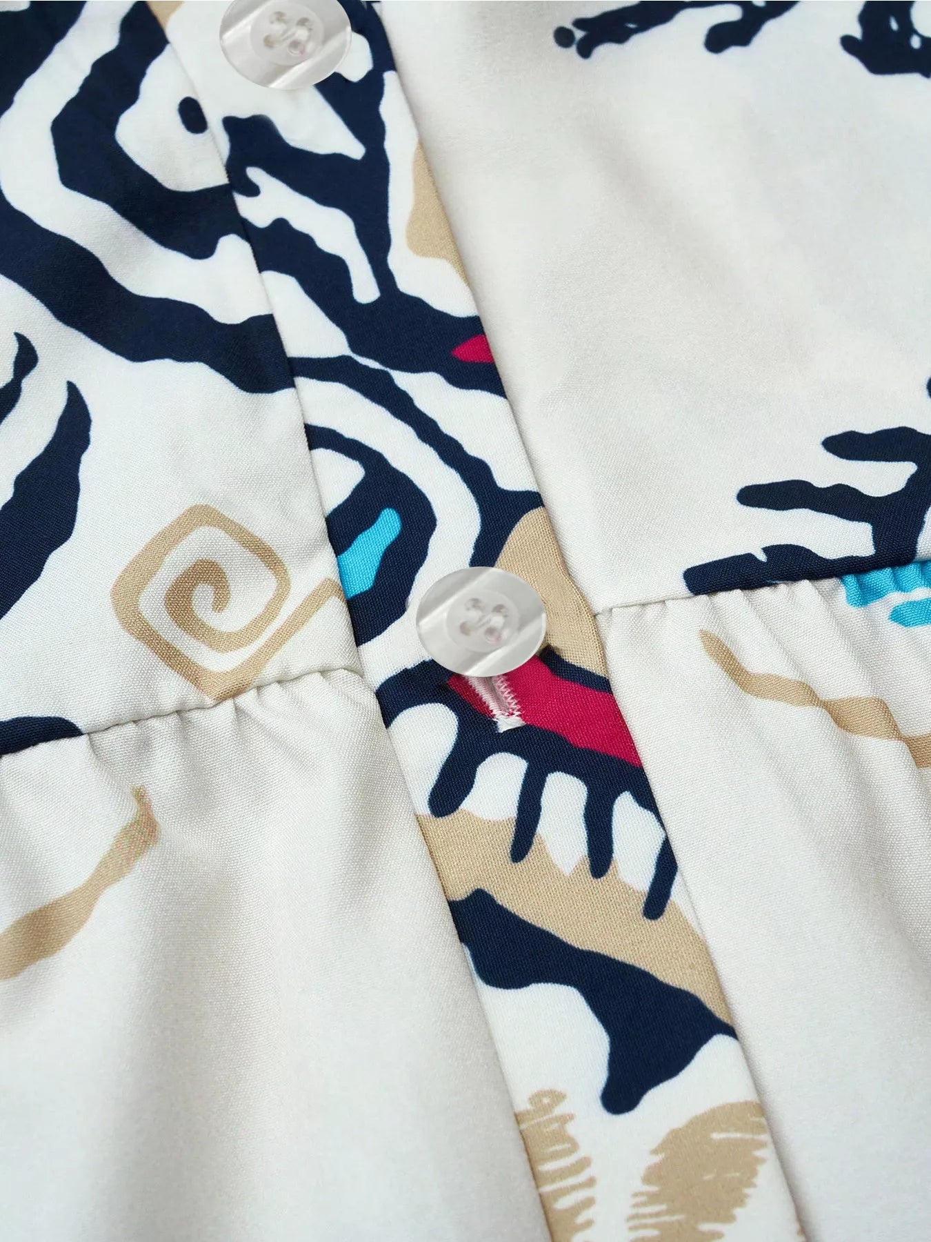 Bohemian print tiered mini dress close-up, button placket and navy blue motifs on white
