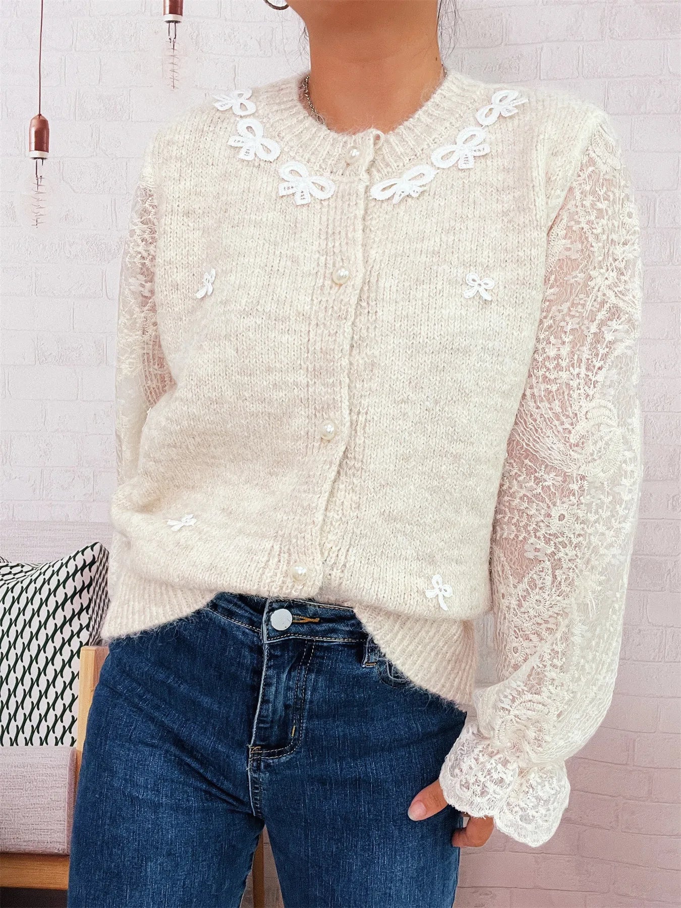 Cream knit cardigan with lace puff sleeves and small embroidered bow accents