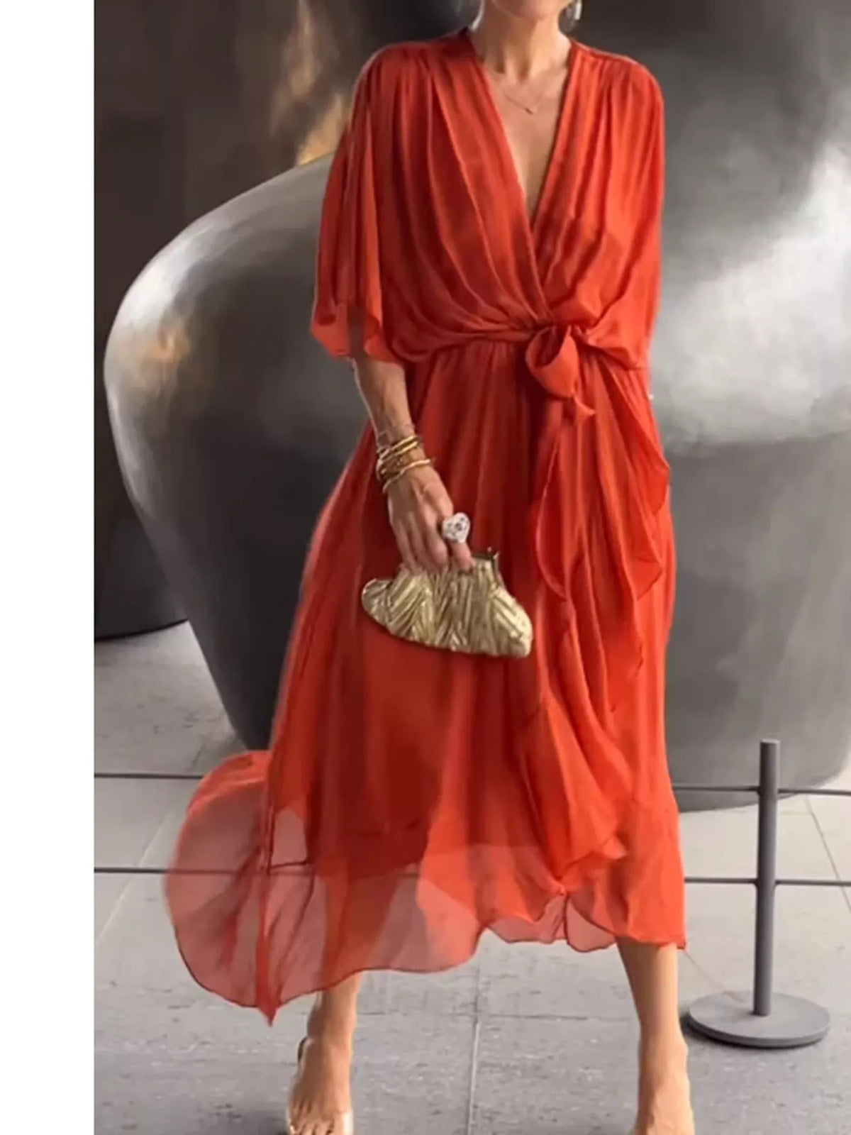 Orange red ruched wrap dress with batwing sleeves and waist tie; tiered sheer midi hem.