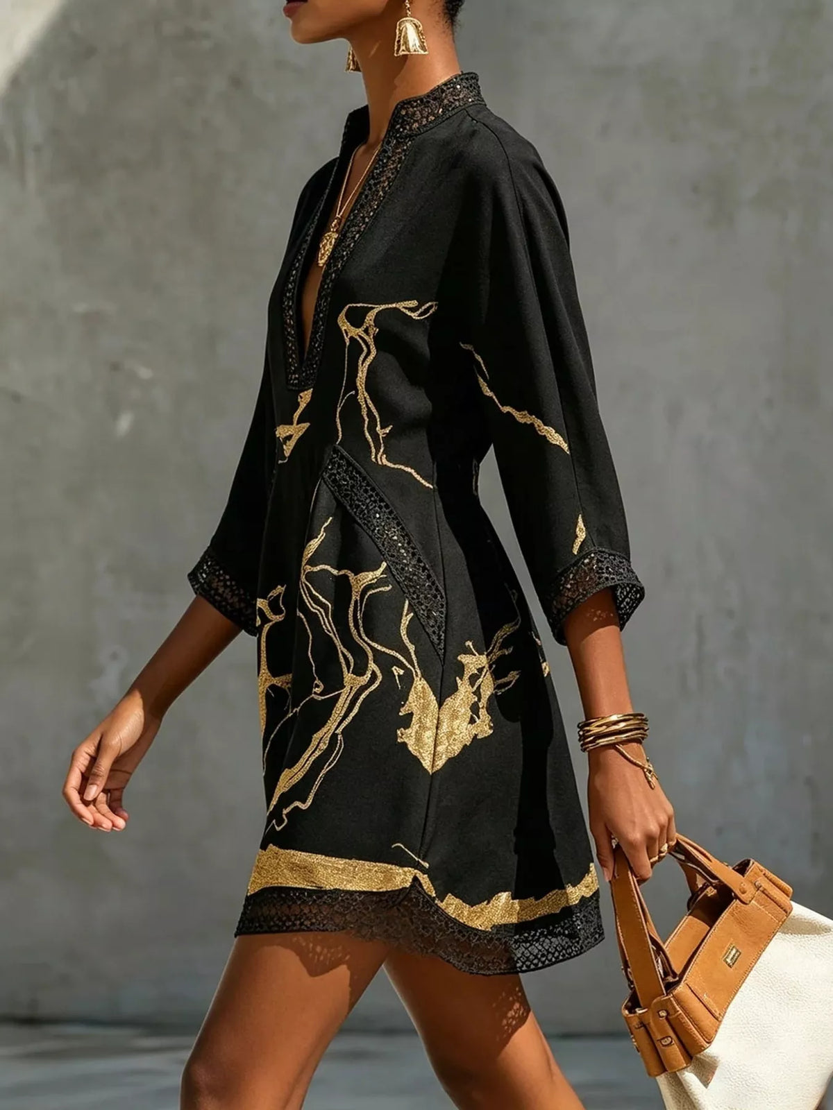 Black mini dress with V-neck lace trim, gold print, and 3/4 sleeves, side view