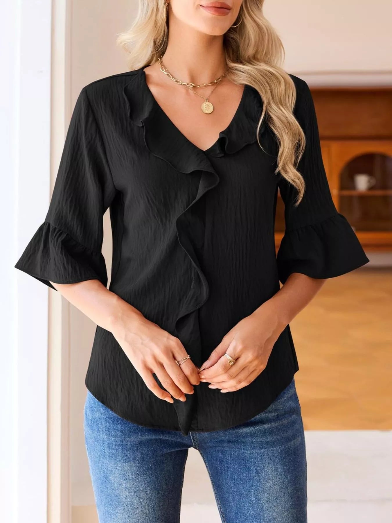 Black ruffle-trim V-neck blouse with layered ruffle front and flared sleeves.
