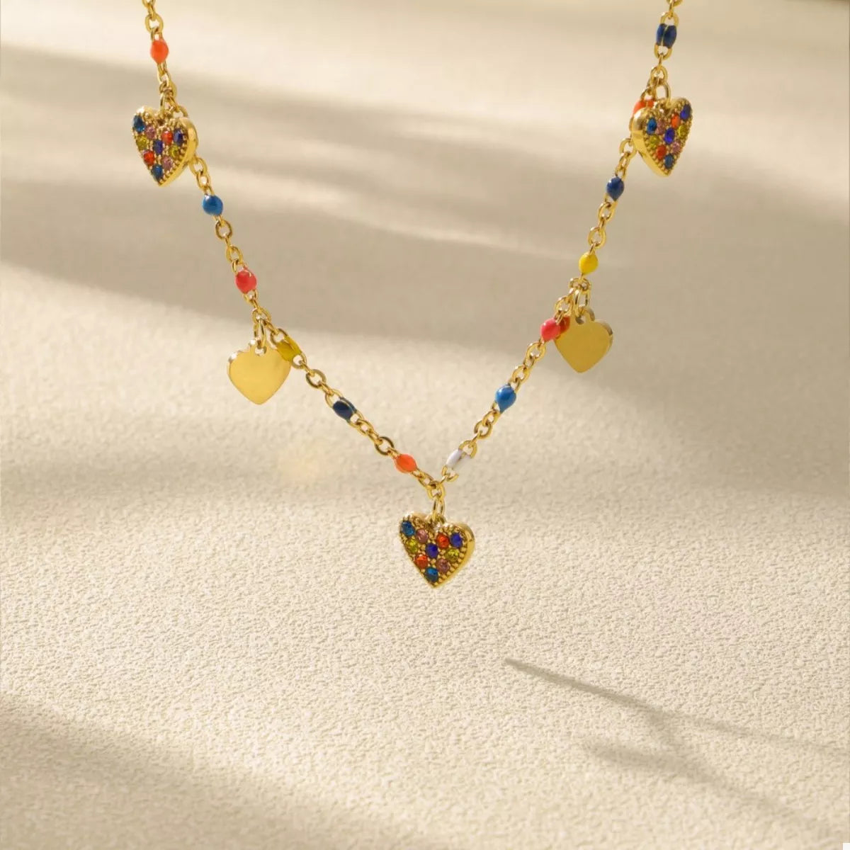 Gold-plated heart charm necklace with blue heart pendant, red dots, and gold hearts