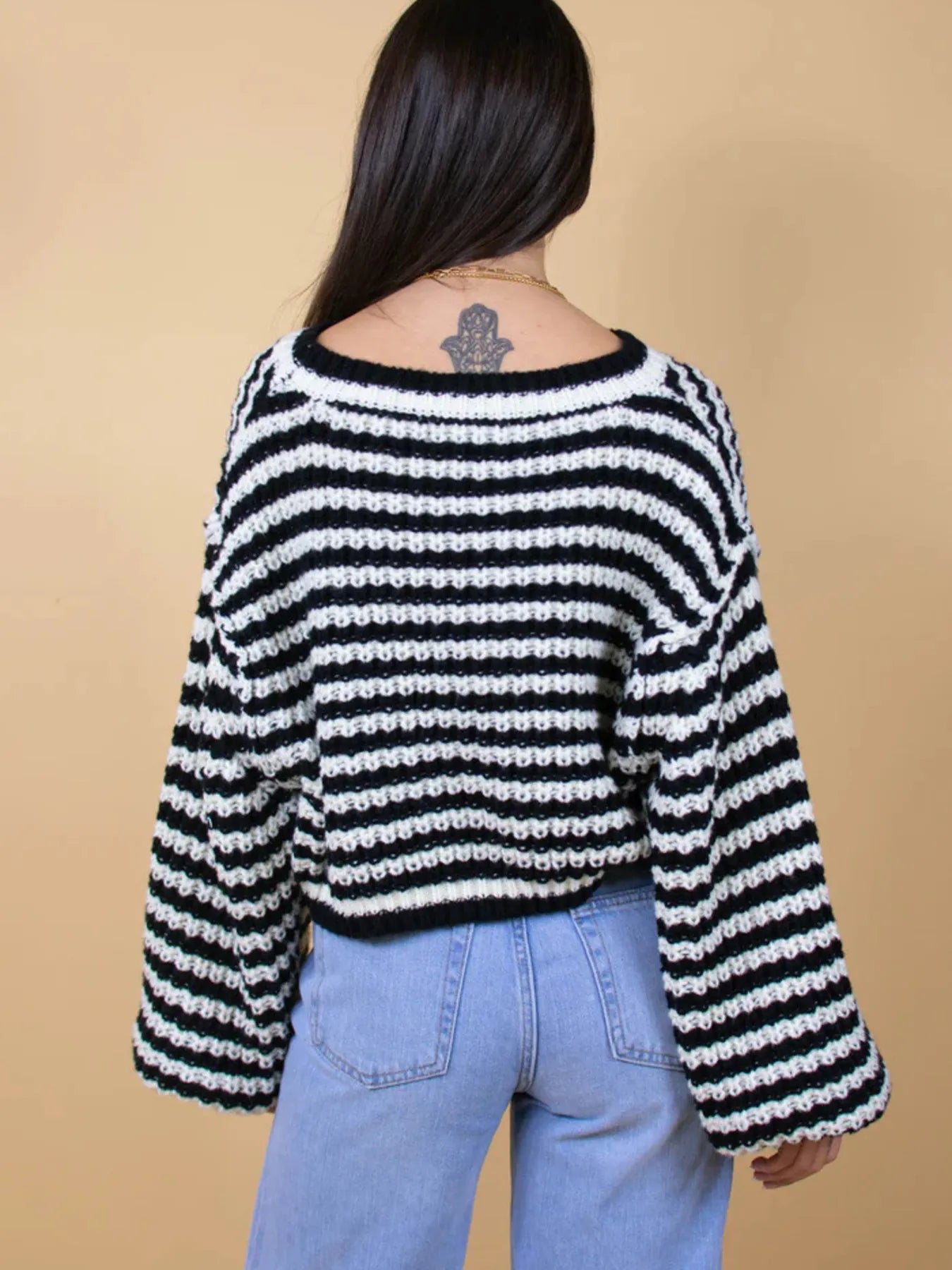 Black-and-white striped drop-shoulder sweater from back view, ribbed crew neck