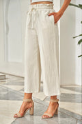 Ivory drawstring paperbag waist wide-leg pants with pleated front and ankle length.