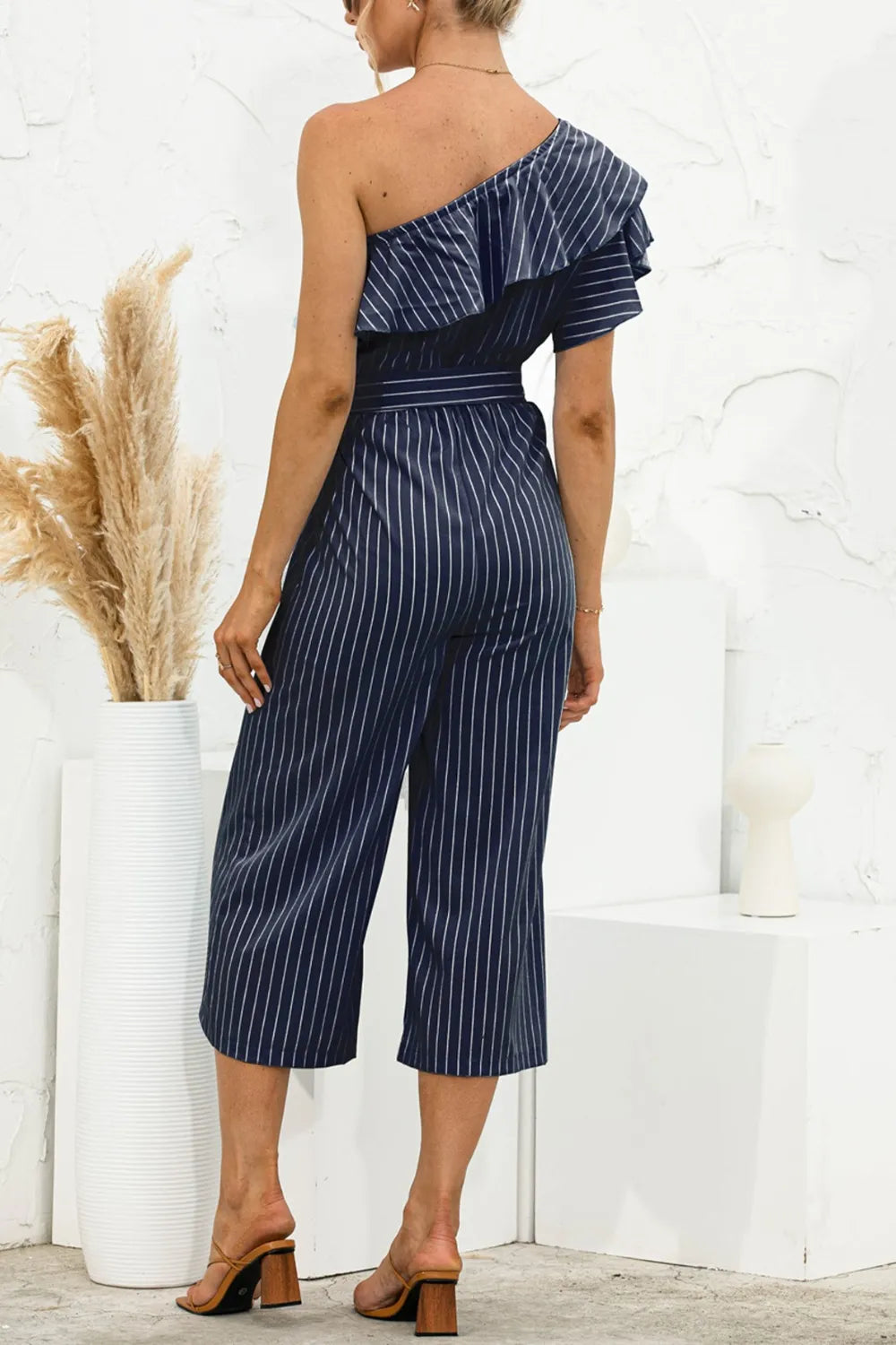 Dark blue pinstripe ruffled one-shoulder jumpsuit with tied waist and wide cropped legs