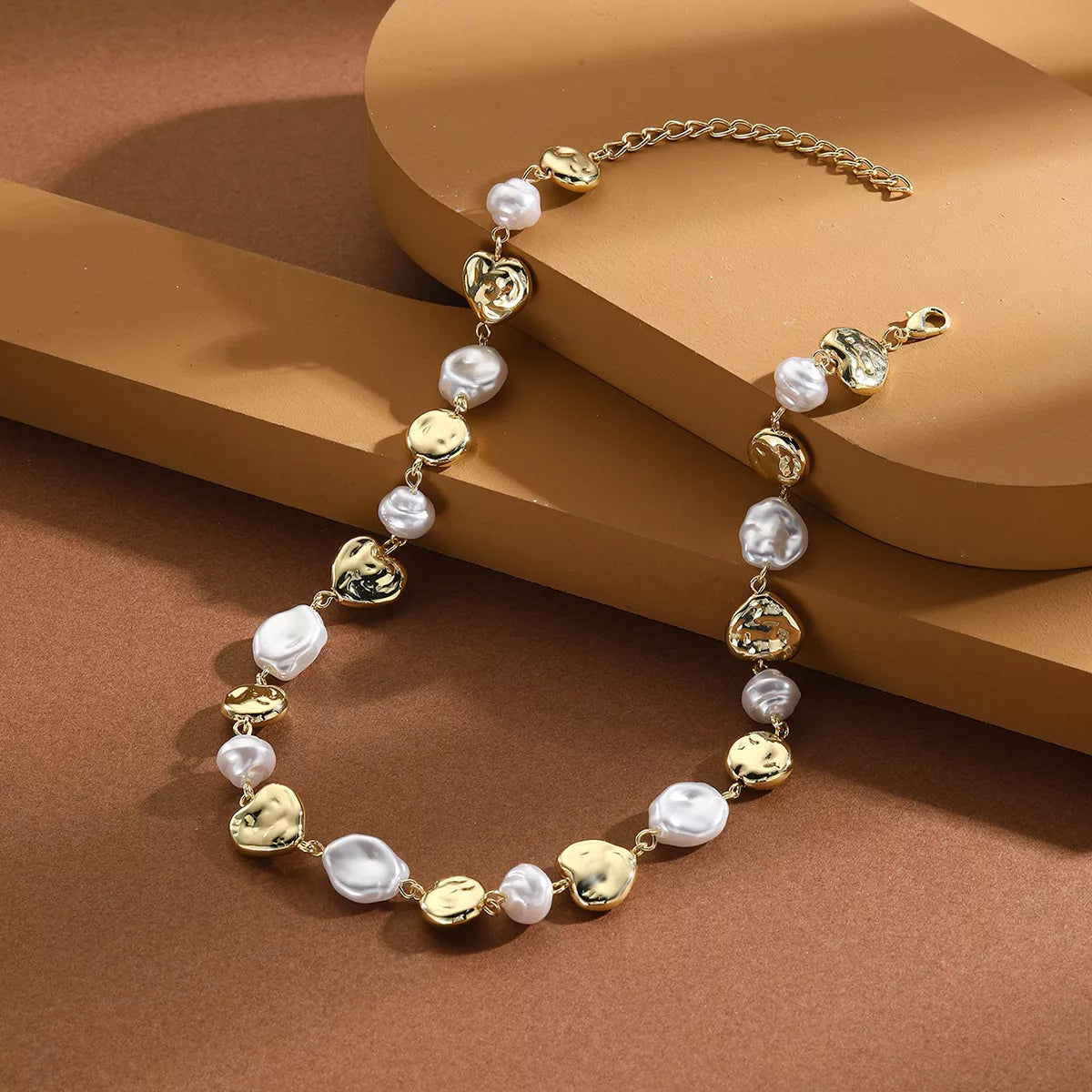 Pearl chain necklace with gold-tone links and rounded pearl beads, shown on a stand